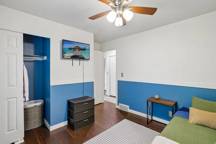 Interior room featuring wood-finish flooring, two-tone wall paint, and a ceiling fan with integrated lighting