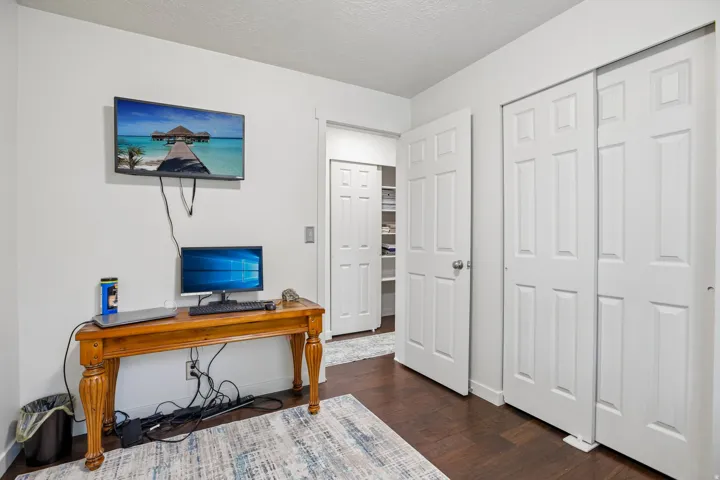 Room featuring dark wood-finish flooring, white walls, and bright overhead lighting