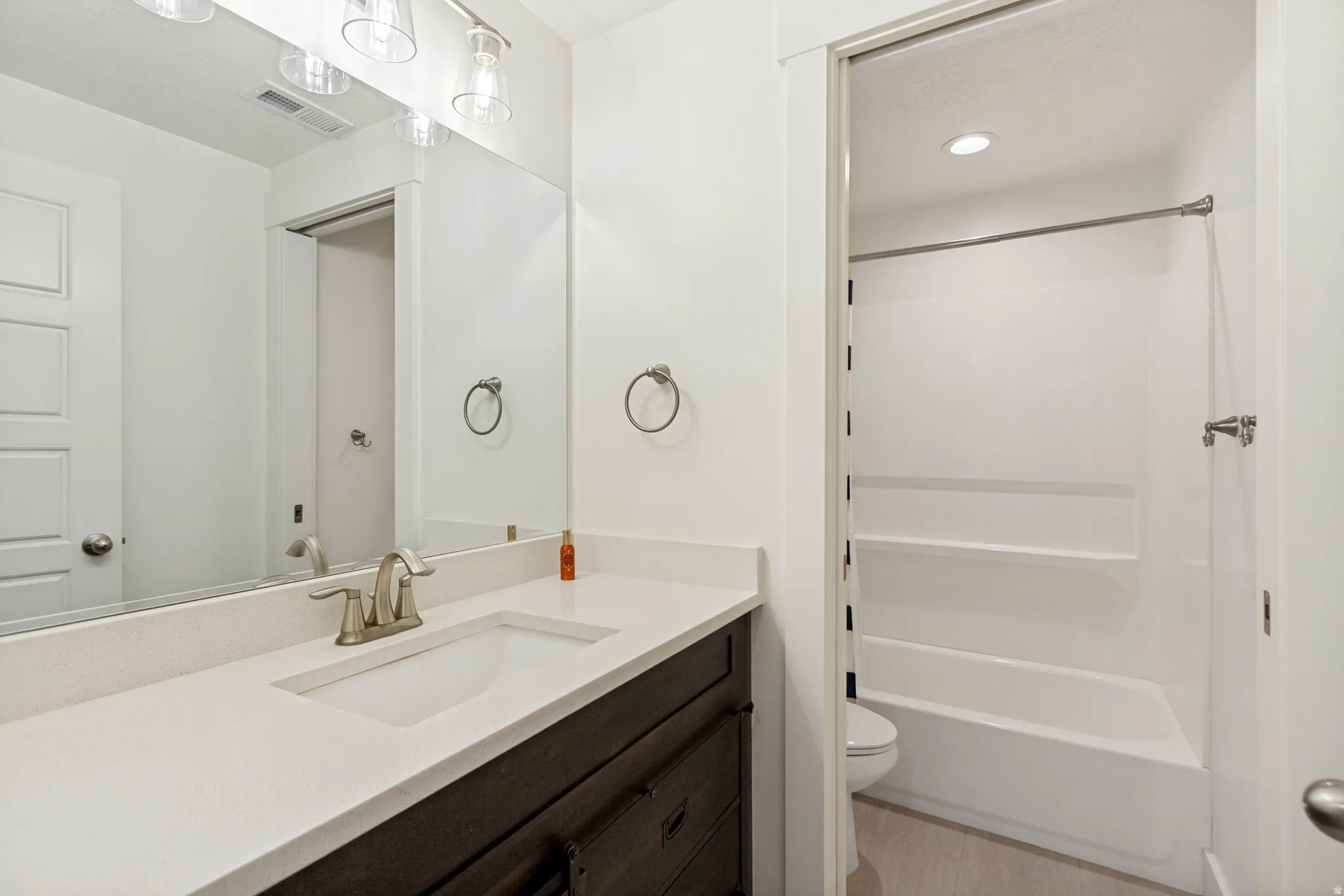 Bathroom featuring a dark wood-finish vanity with a light countertop, an undermount sink, and brushed nickel fixtures
