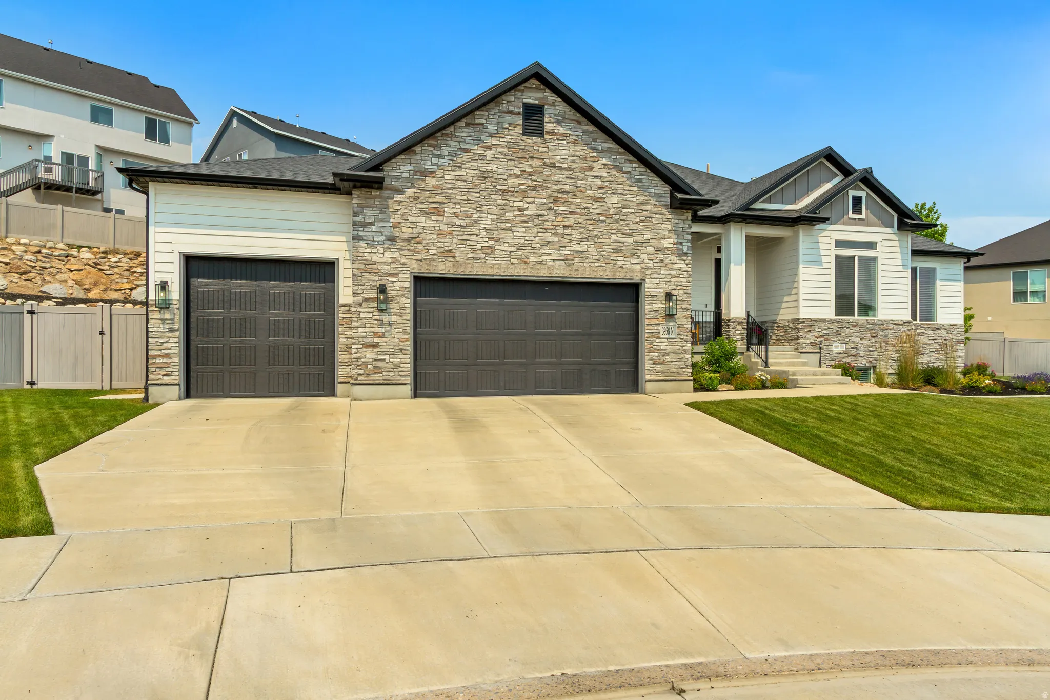 Contemporary home with a stone and siding exterior, a two-car garage, and a concrete driveway
