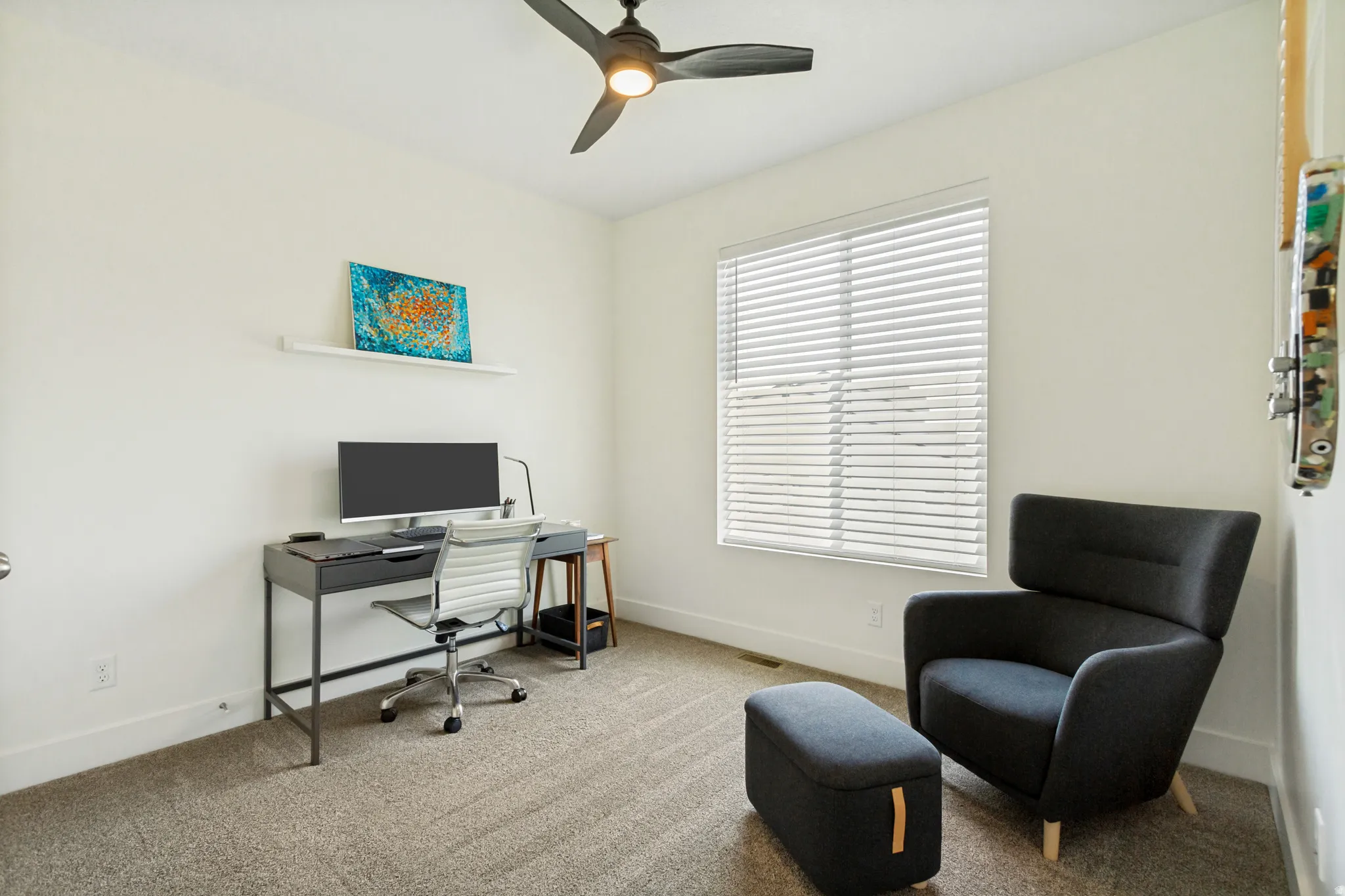 Bedroom featuring light-colored walls, textured carpet flooring, and a ceiling fan with integrated lighting