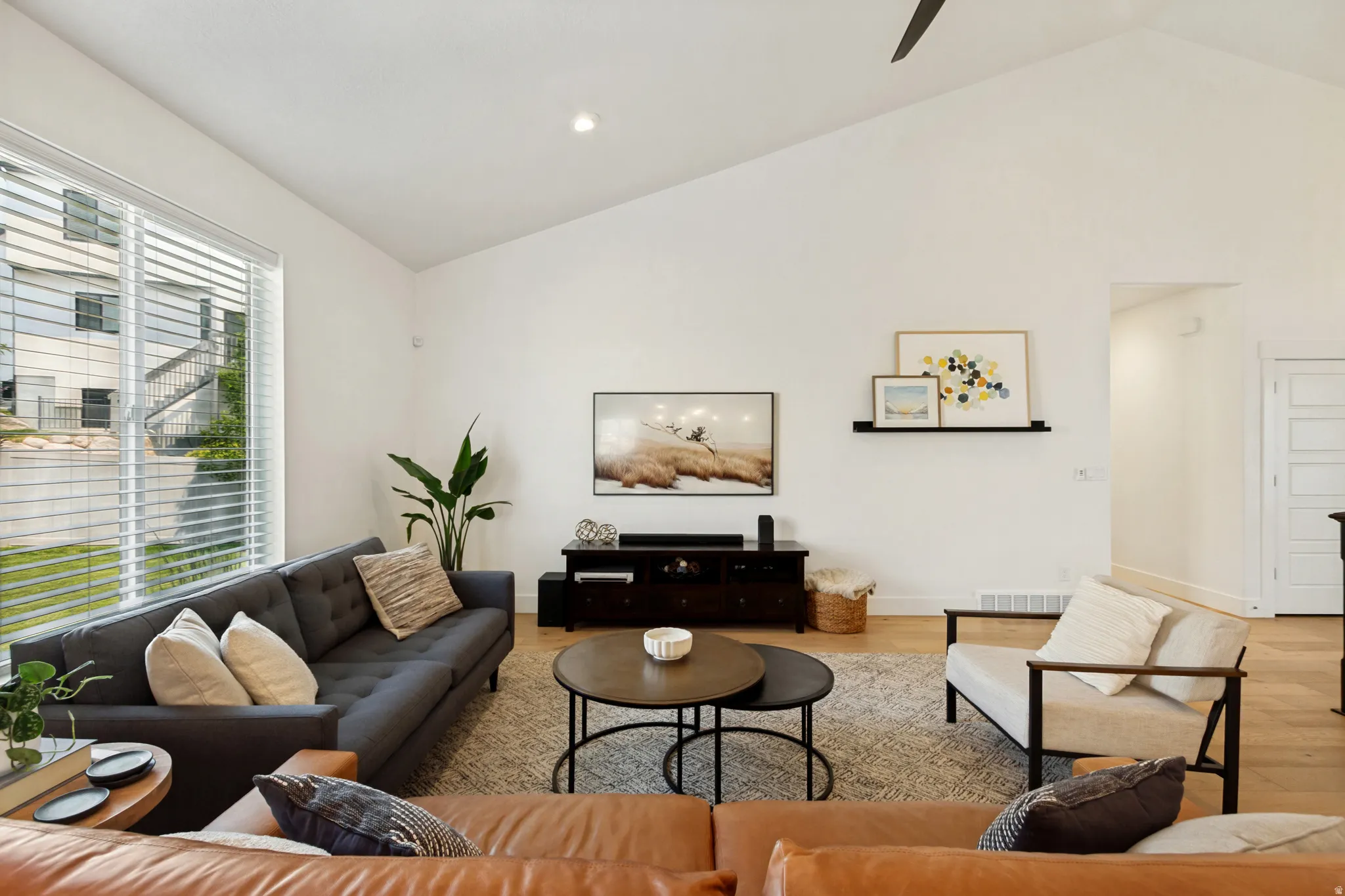Spacious living area featuring a vaulted ceiling and wood-finish flooring