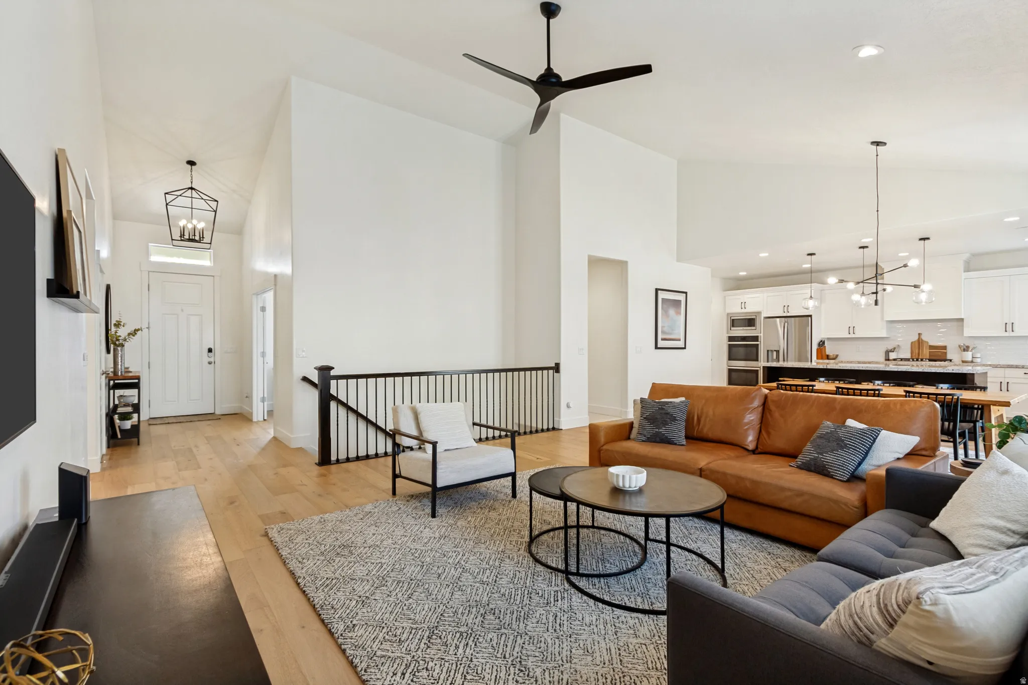 Vaulted living area featuring light wood-finish flooring and a contemporary ceiling fan