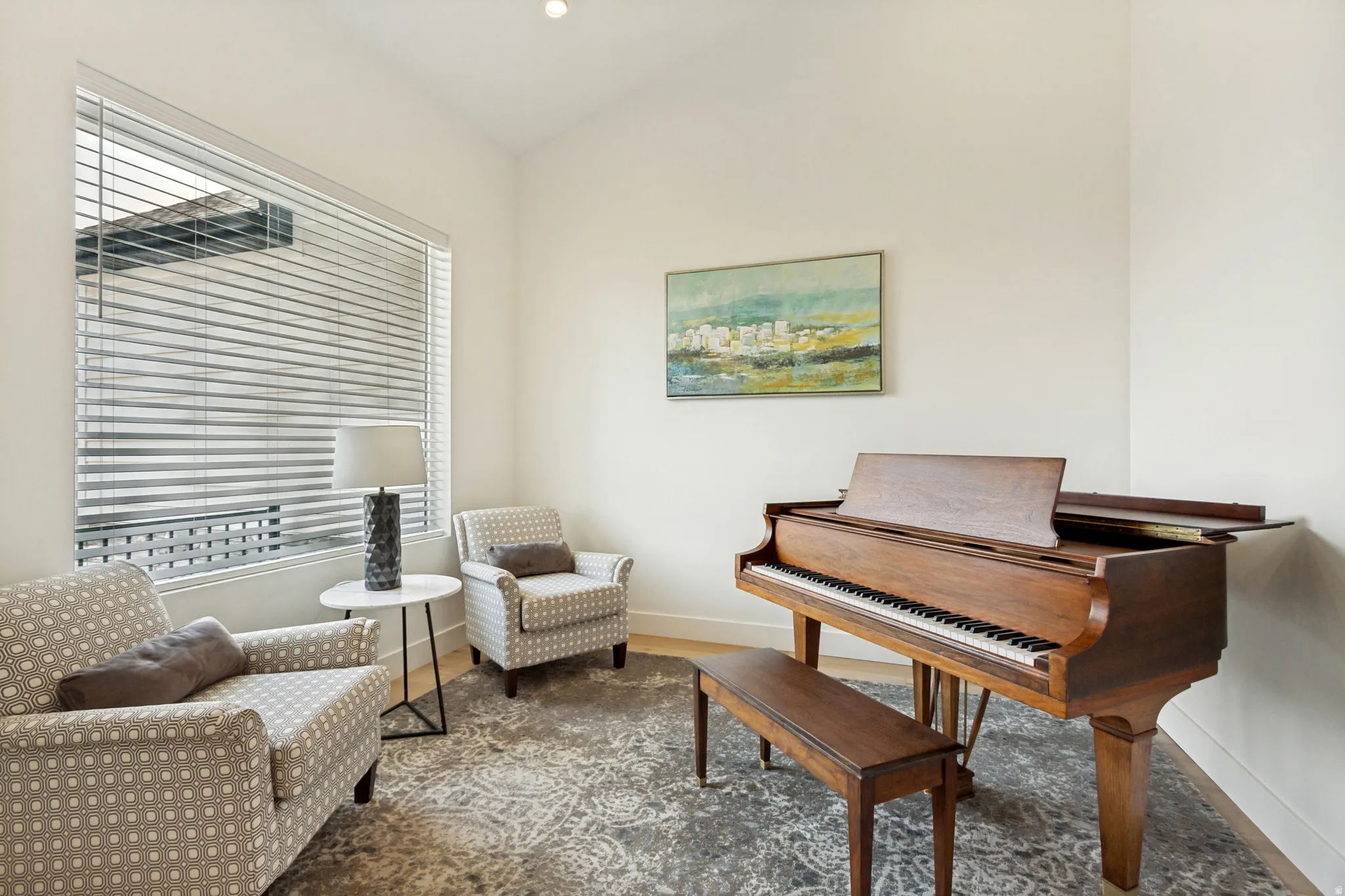 Bright interior space featuring a large window with horizontal blinds, light wood-finish flooring, and recessed ceiling lighting