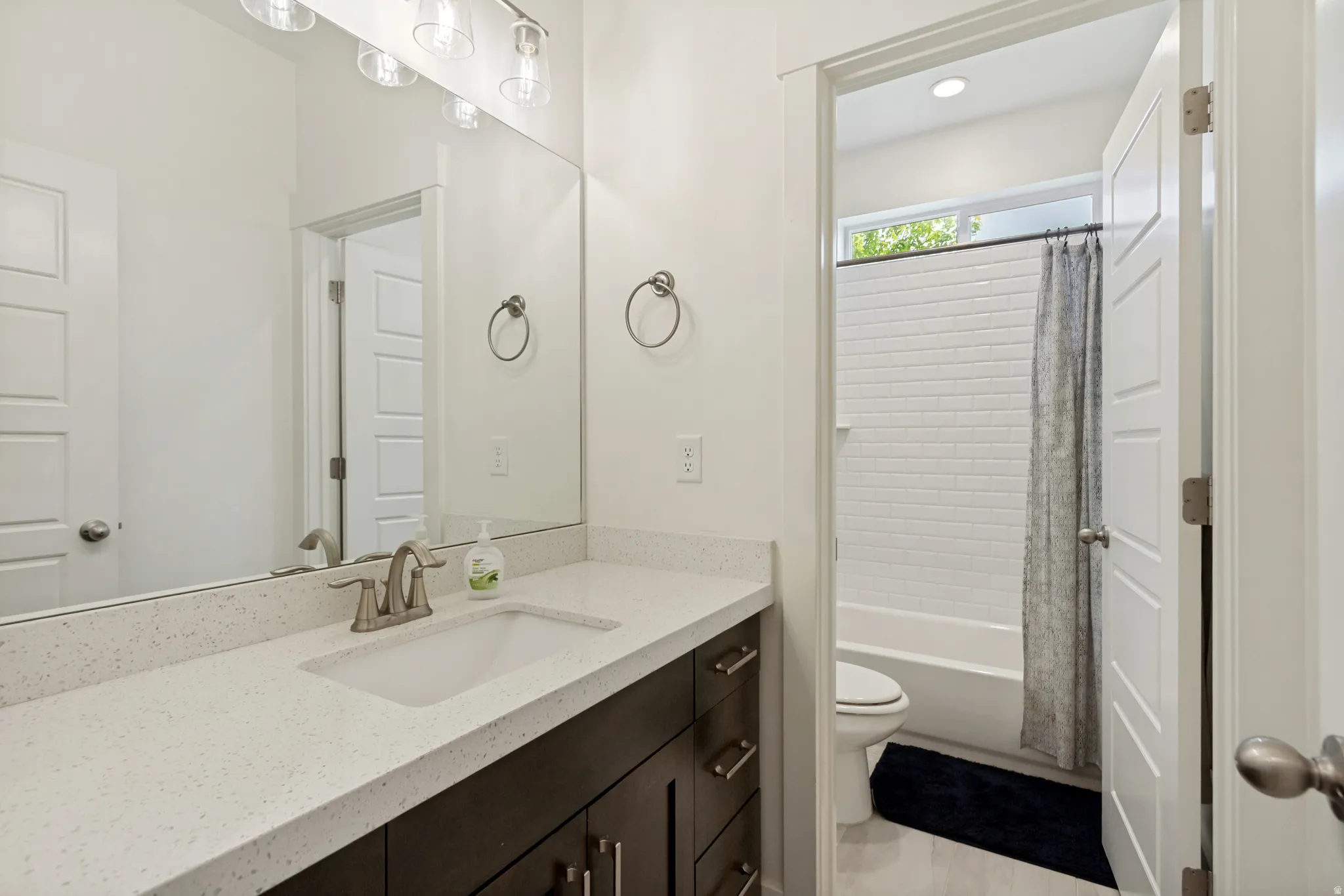 Bathroom featuring a vanity with a white composite countertop, undermount sink, and brushed nickel faucet