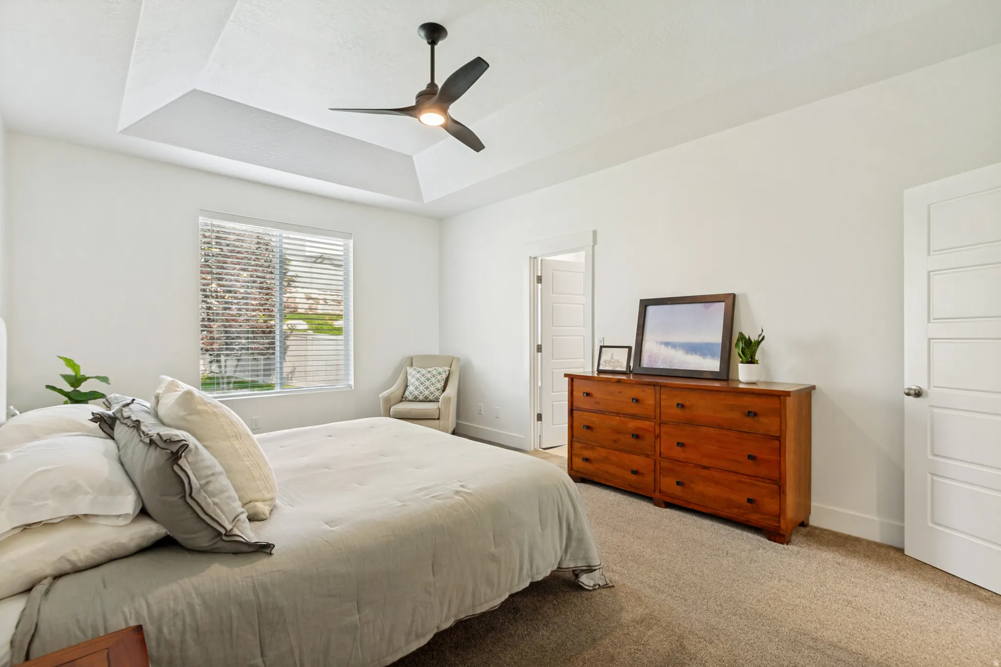 Recessed ceiling with a contemporary ceiling fan, white paneled doors, window with horizontal blinds, and carpeting
