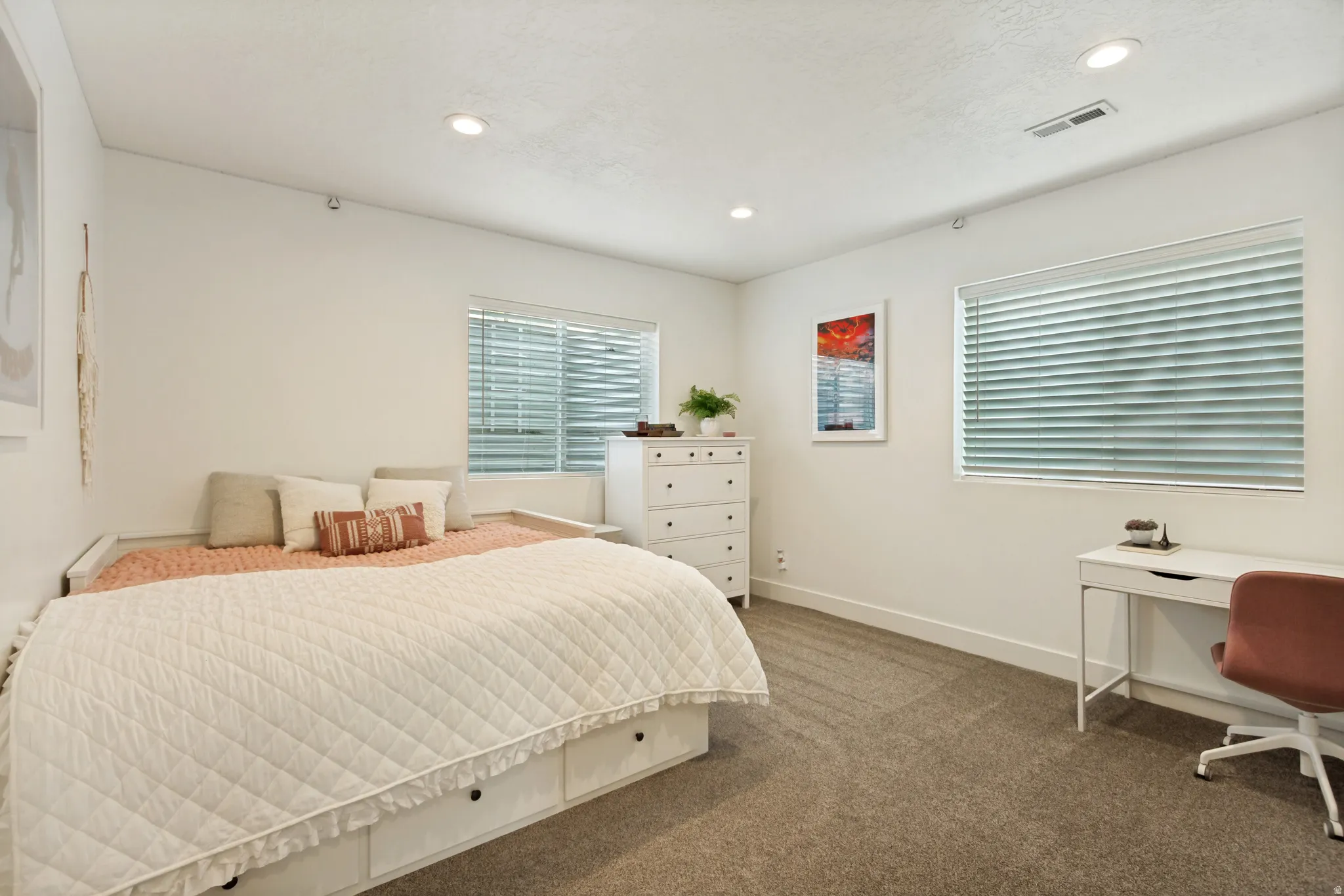 Spacious room featuring carpet flooring, crisp white walls, recessed lighting, and two windows with blinds