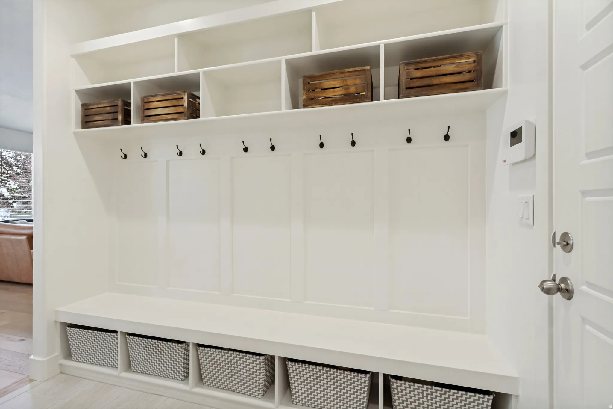 Built-in mudroom featuring a bench, individual cubbies, upper shelving, and coat hooks