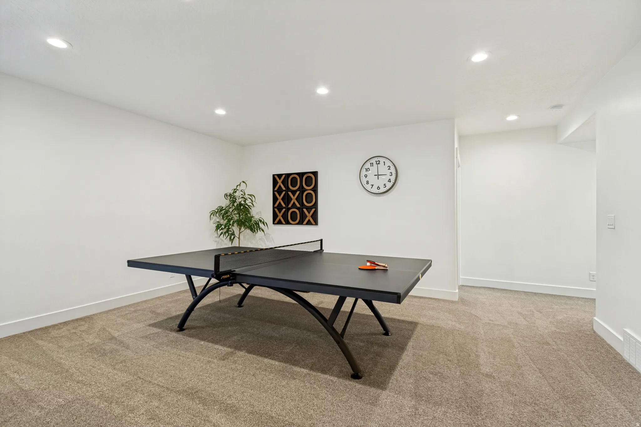 Spacious interior room featuring plush carpet flooring, recessed ceiling lighting, and crisp white walls
