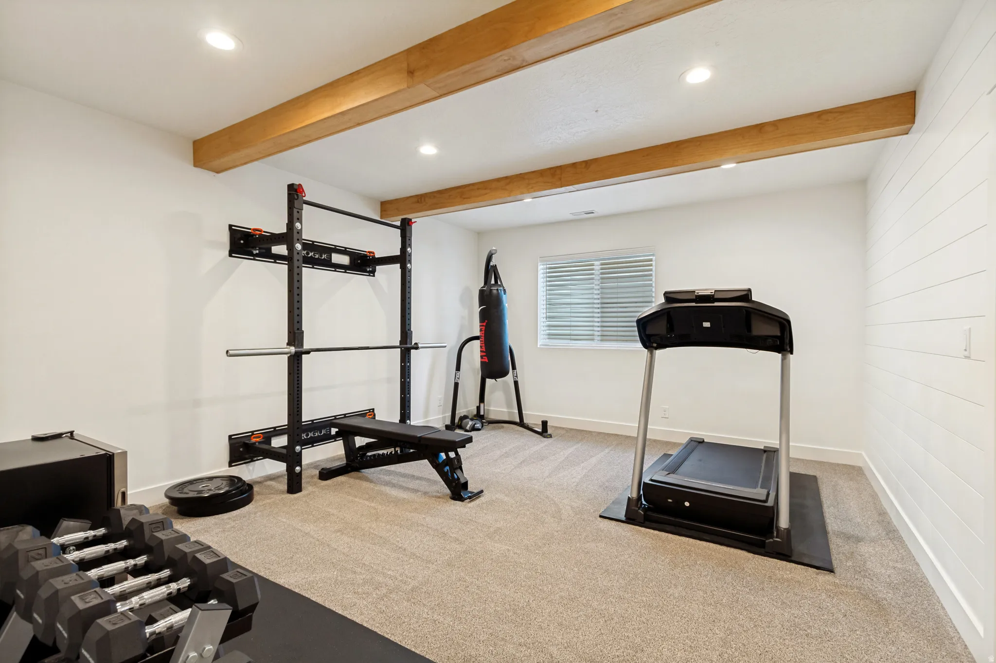 Dedicated room featuring exposed wood beams, recessed lighting, a window with blinds, and shiplap accent wall