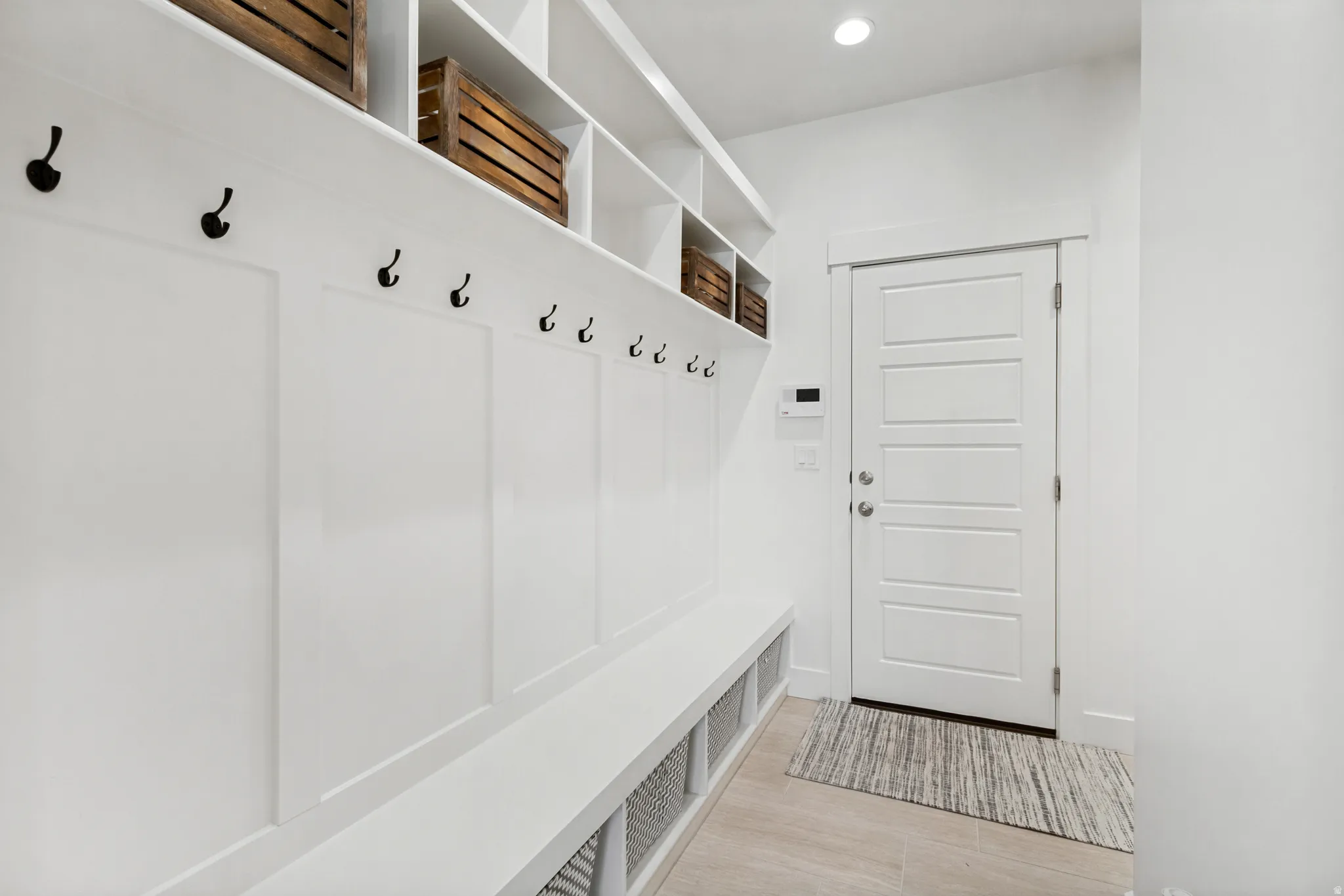Built-in mudroom organization featuring bench seating, storage cubbies, wall hooks, and upper shelving