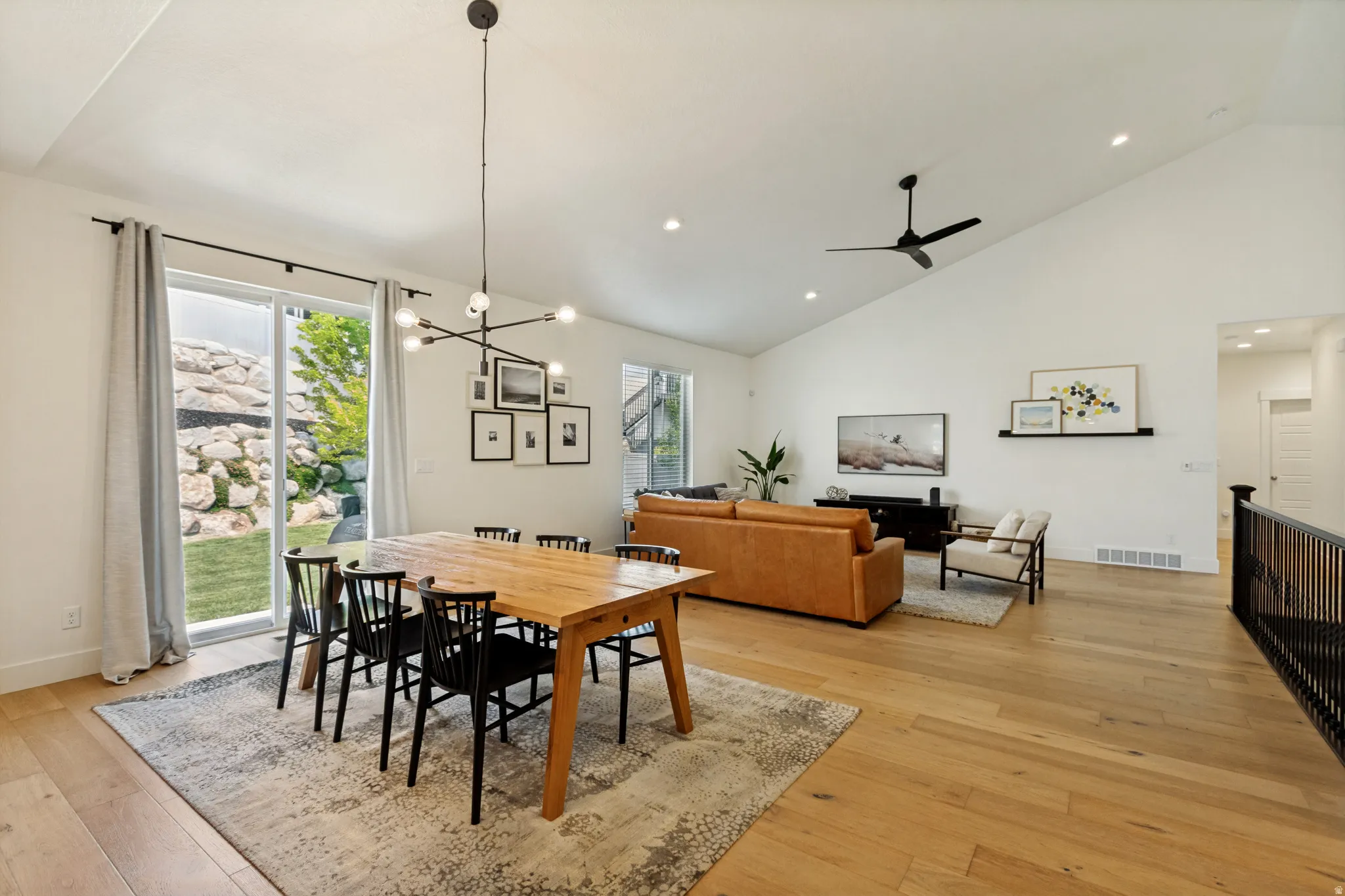 Open-concept living space featuring wood-finish flooring, a vaulted ceiling with recessed lighting, and a modern chandelier