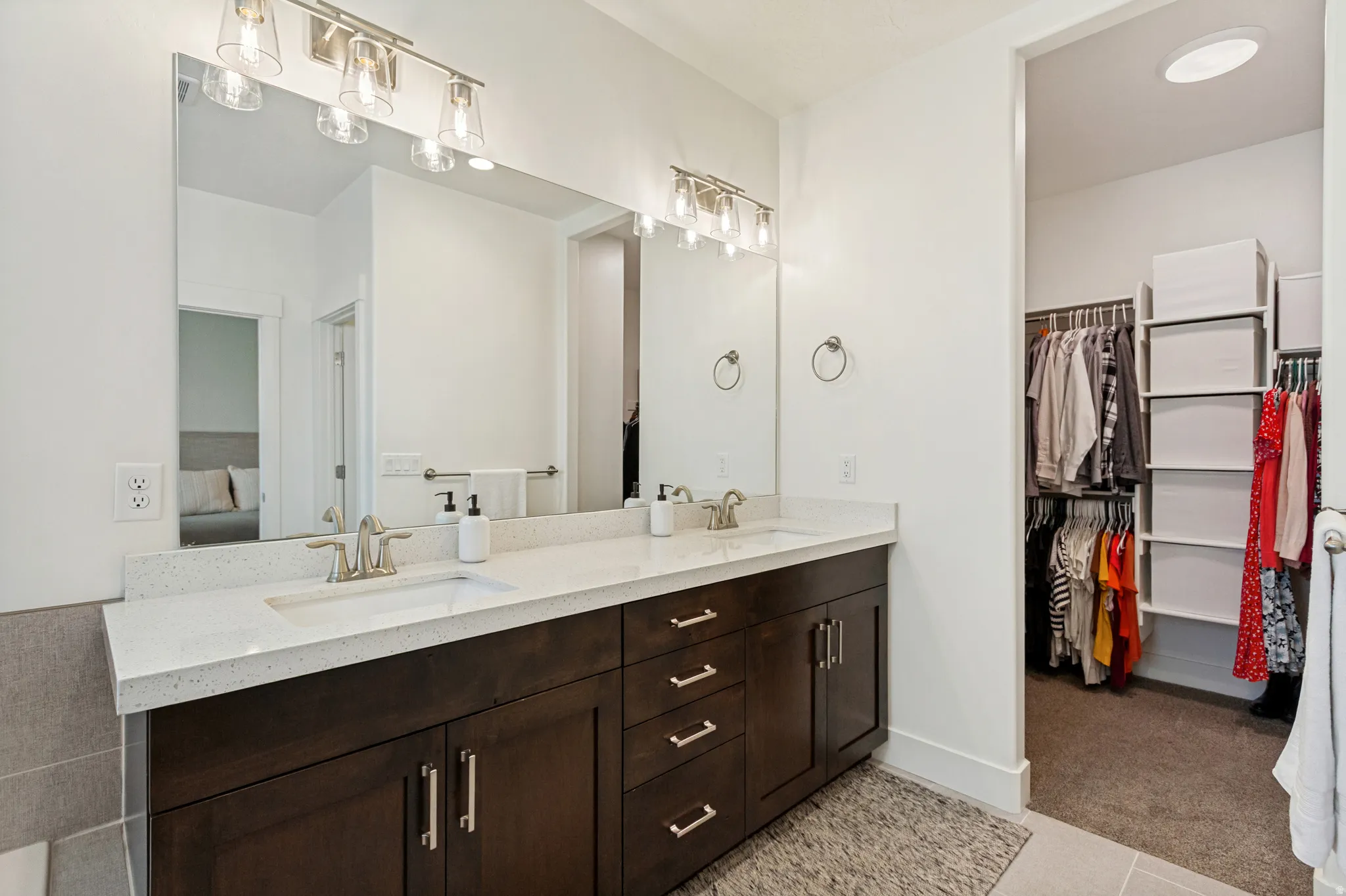 Bathroom featuring a double vanity with dark wood-finish cabinetry, light-toned countertops, and dual rectangular undermount sinks