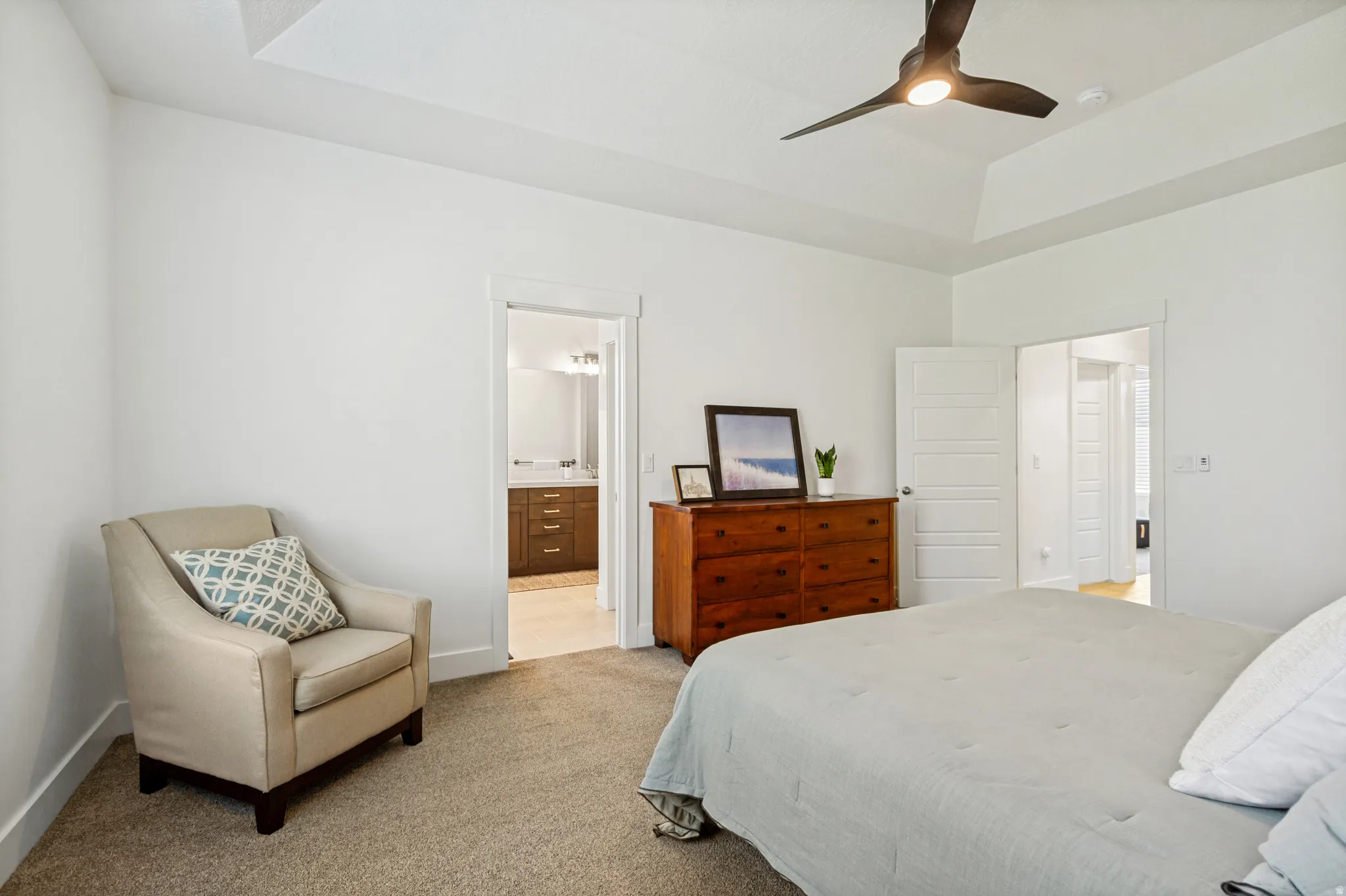 Spacious bedroom with a tray ceiling and a contemporary ceiling fan