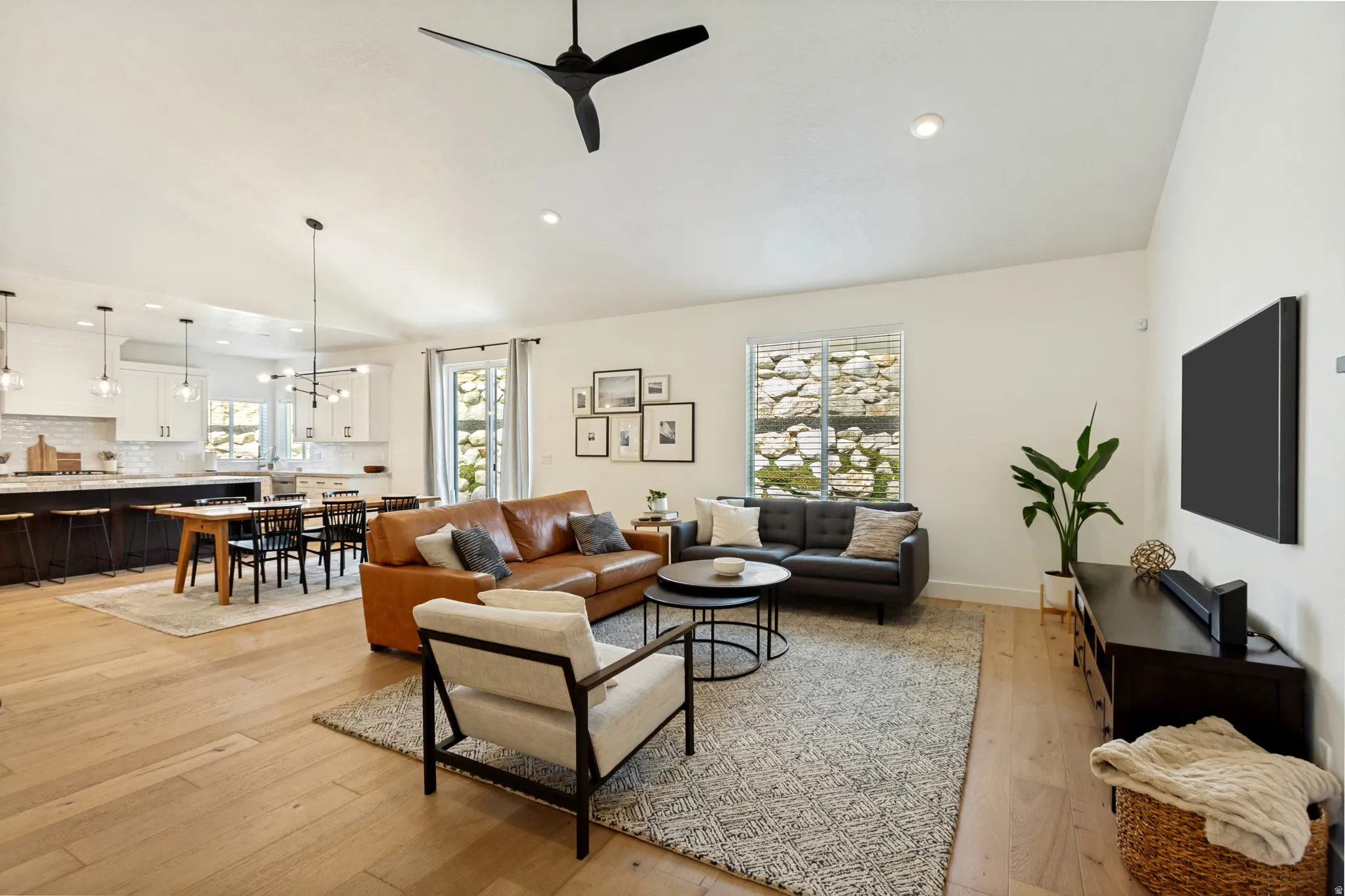 Spacious living area featuring light wood-finish flooring, vaulted ceilings, and recessed lighting
