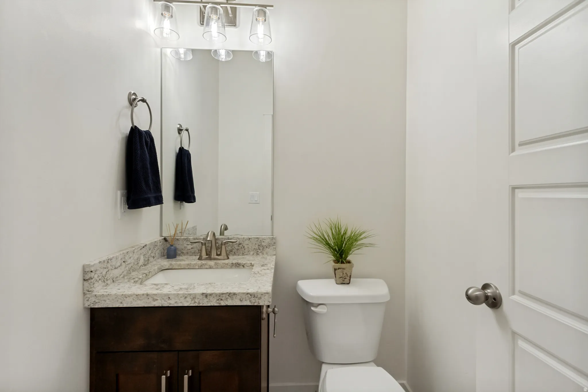 Vanity with a granite countertop, undermount sink, and brushed nickel faucet
