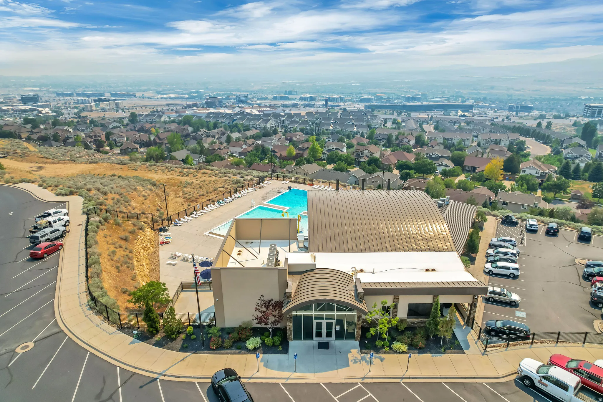 Recreational facility featuring an outdoor swimming pool, a large arched-roof structure, and extensive paved parking areas