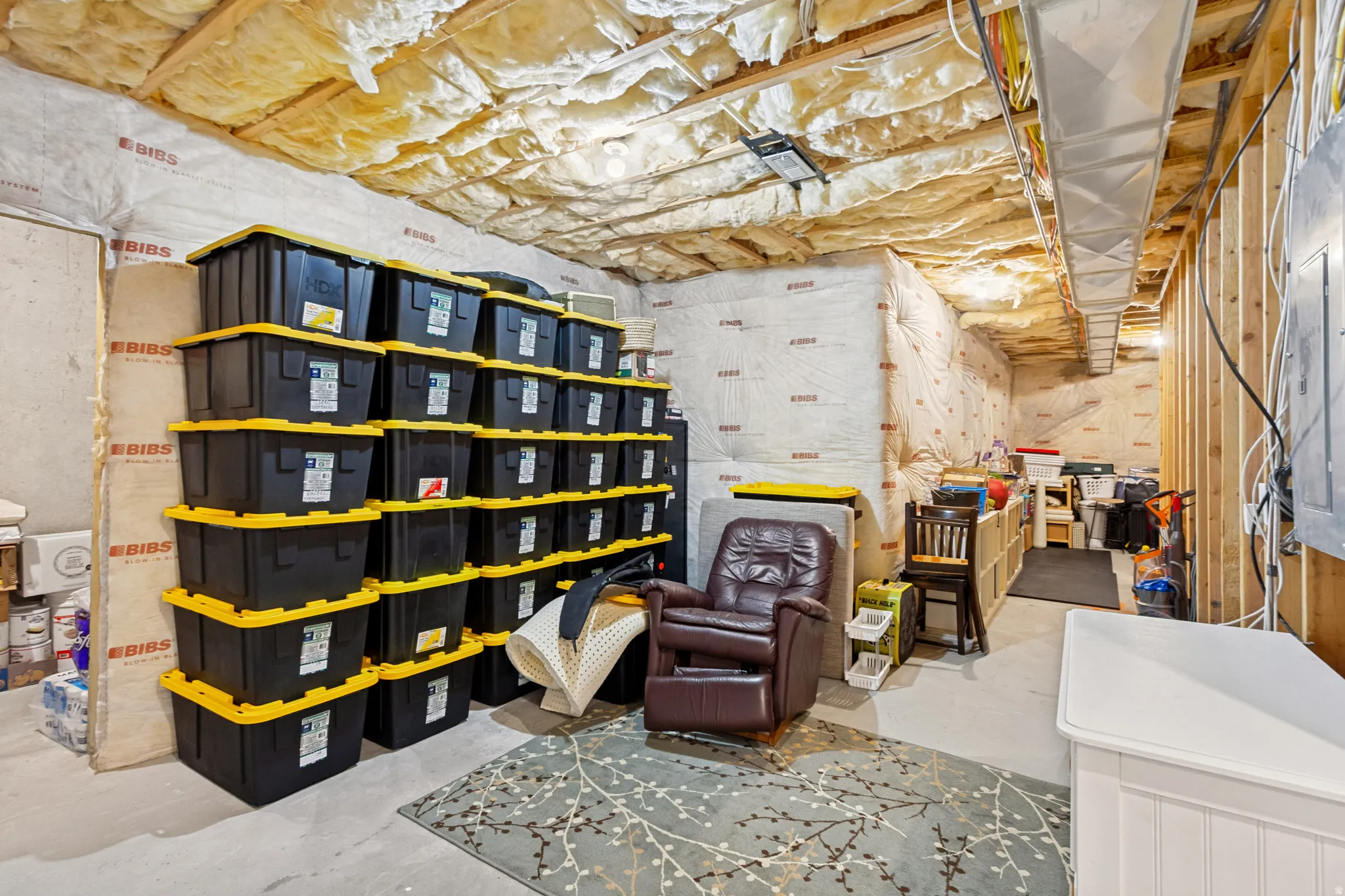 Unfinished basement space featuring exposed wooden framing, visible insulation, and concrete flooring