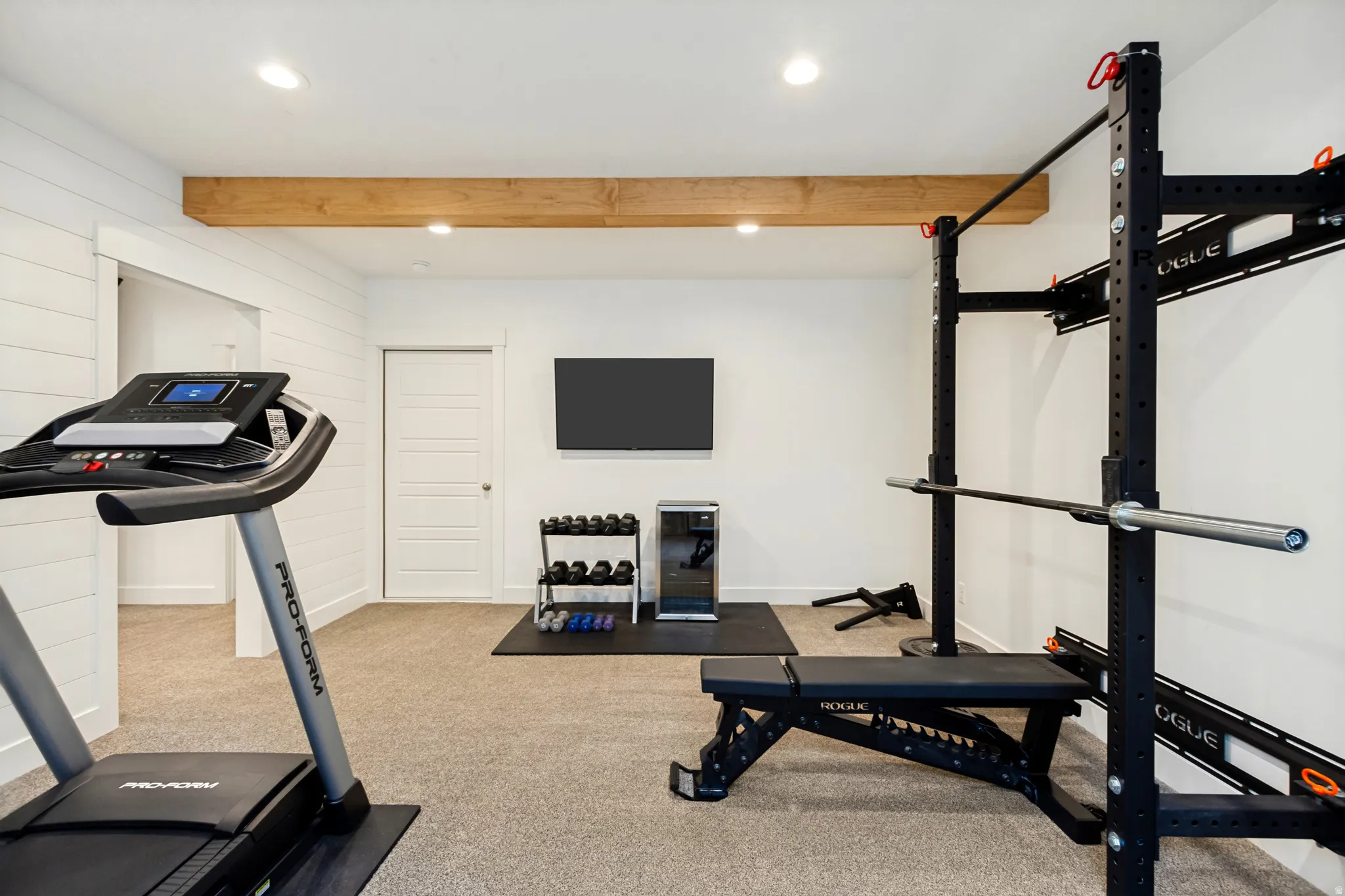 Open-concept recreation area featuring shiplap accent walls, recessed lighting, and a prominent wood-finish beam