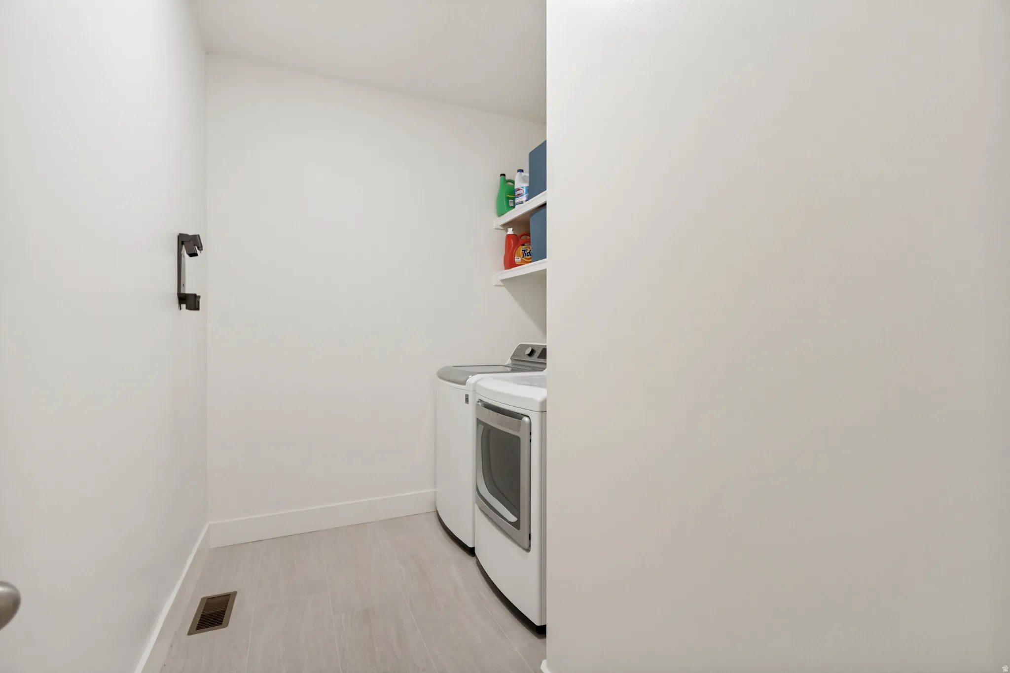 Dedicated laundry space featuring wood-finish flooring, white walls, and built-in shelving
