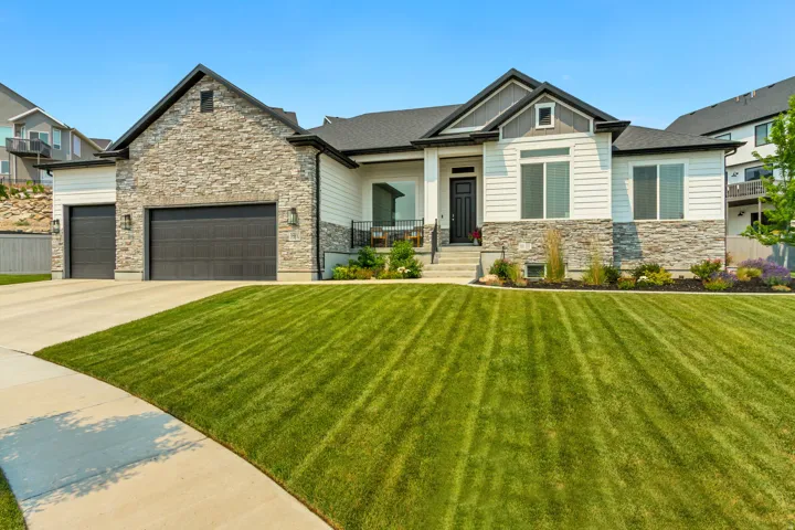 Modern ranch-style residence featuring a prominent stone and horizontal siding facade, a dark shingle roof, and a covered entry porch