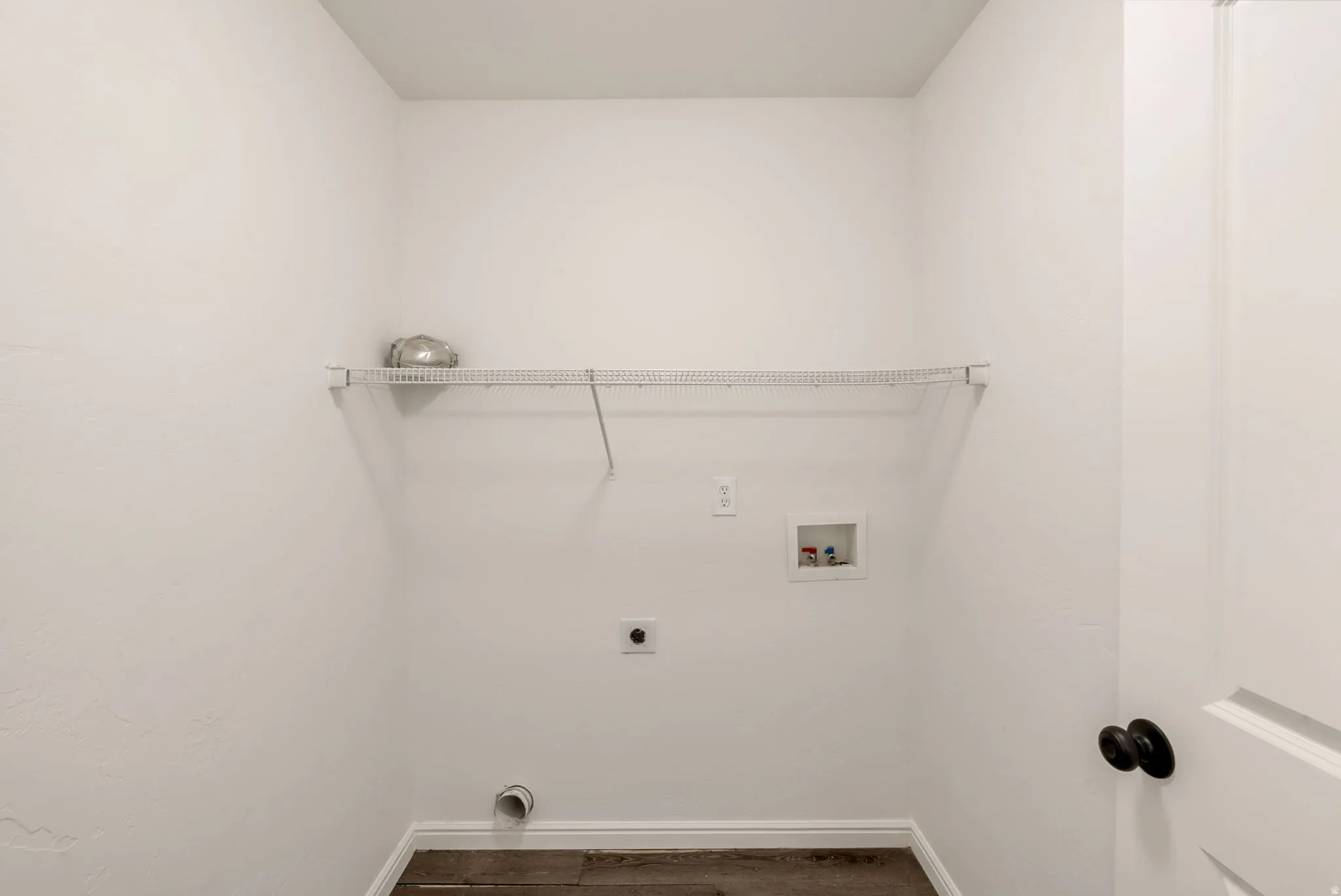 Dedicated utility space featuring a wire shelving unit, appliance hookups, and wood-finish flooring