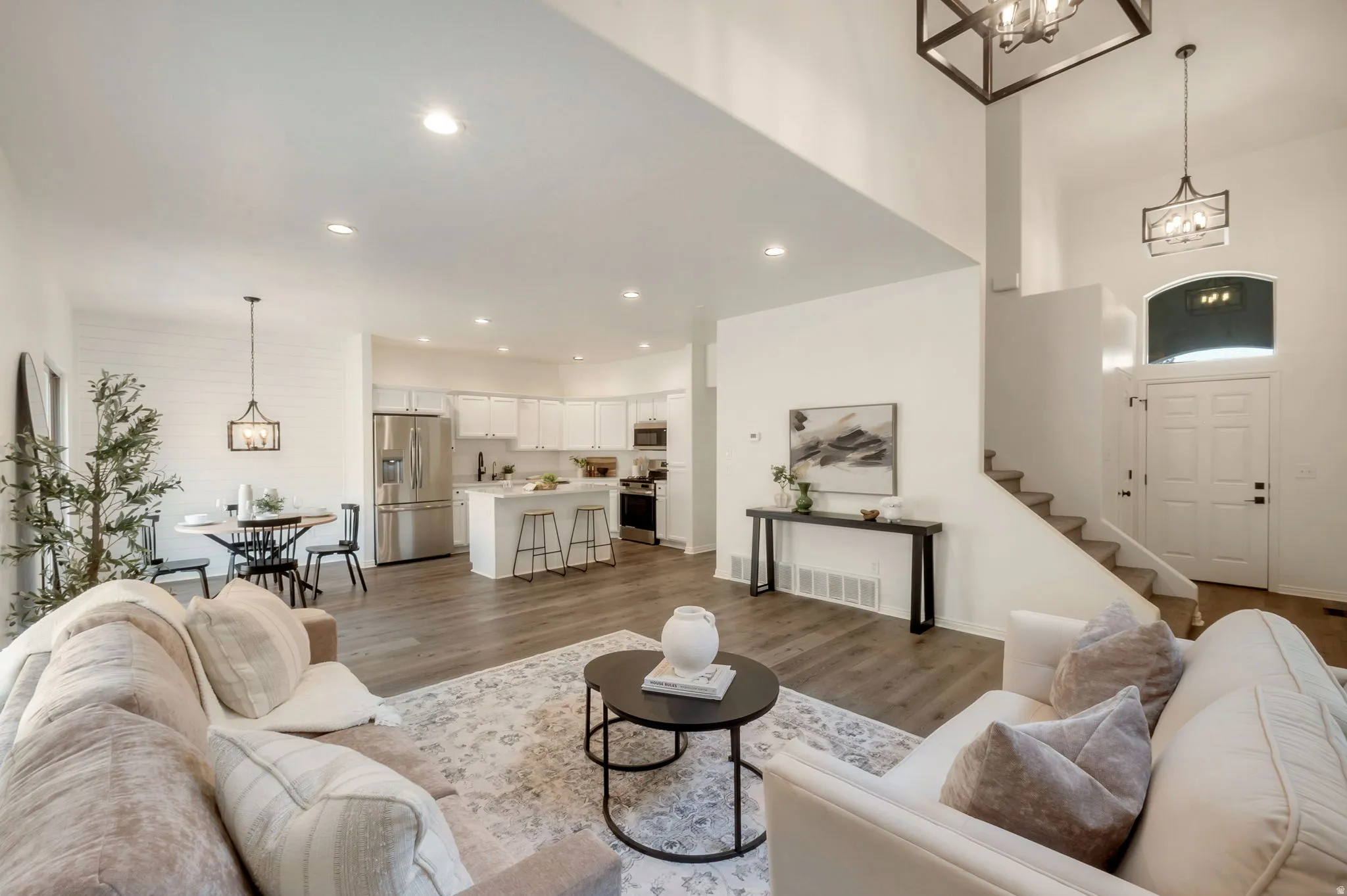 Expansive living area featuring high ceilings, wood-finish flooring, and recessed lighting