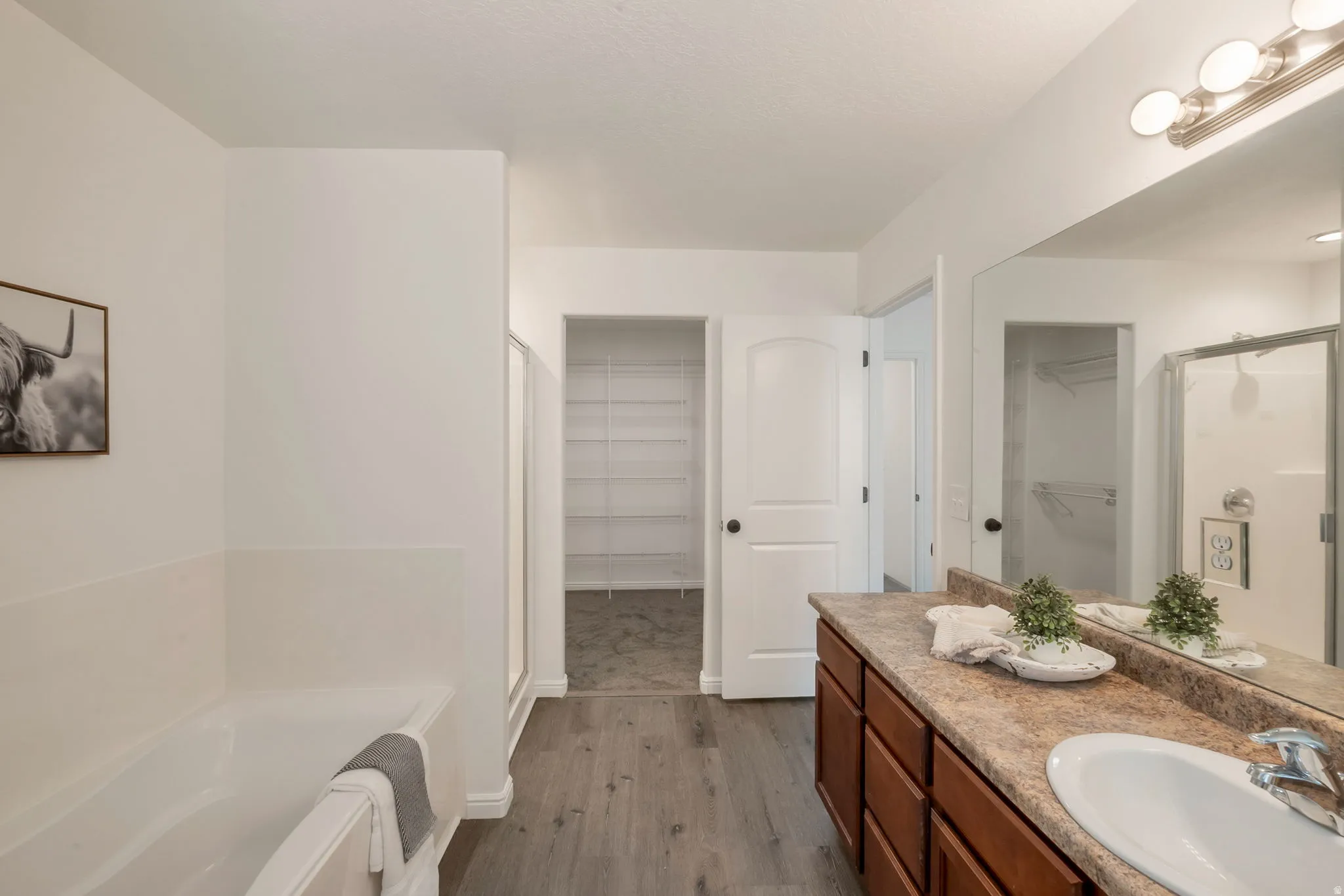 Bathroom featuring a single vanity with an integrated sink, wood-finish cabinetry, and a framed mirror