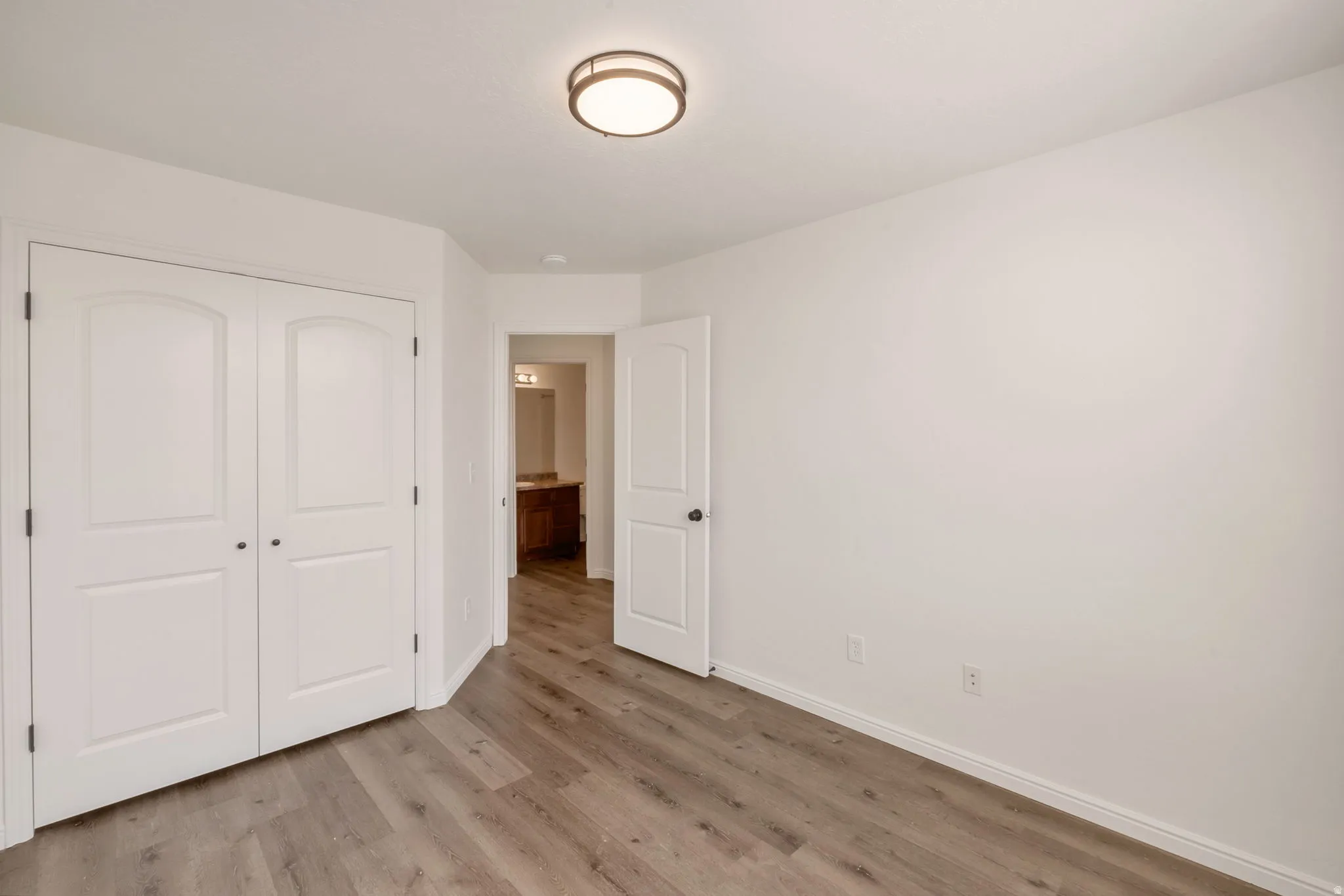 Room featuring wood-finish flooring, white walls, and a flush-mount ceiling light