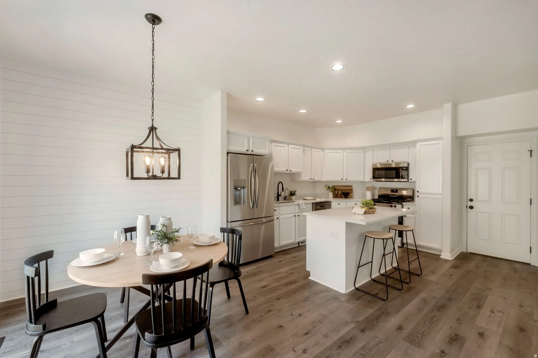Open-concept kitchen and dining area featuring wood-finish flooring, recessed lighting, and a kitchen island with seating