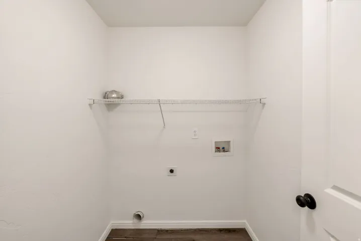 Dedicated utility space featuring a wire shelving unit, appliance hookups, and wood-finish flooring