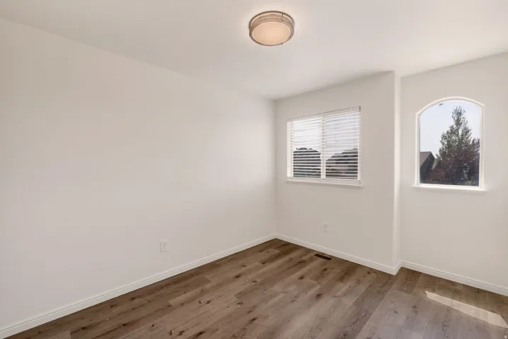 Room featuring wood-finish flooring, crisp white walls, and a recessed ceiling light fixture
