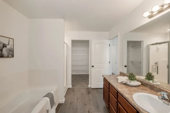 Bathroom featuring a single vanity with an integrated sink, wood-finish cabinetry, and a framed mirror