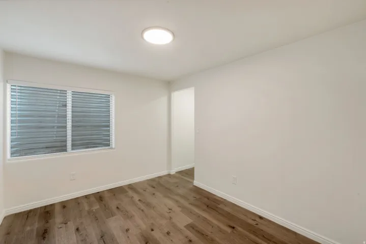 Room featuring wood-finish flooring, white walls, and a recessed ceiling light fixture