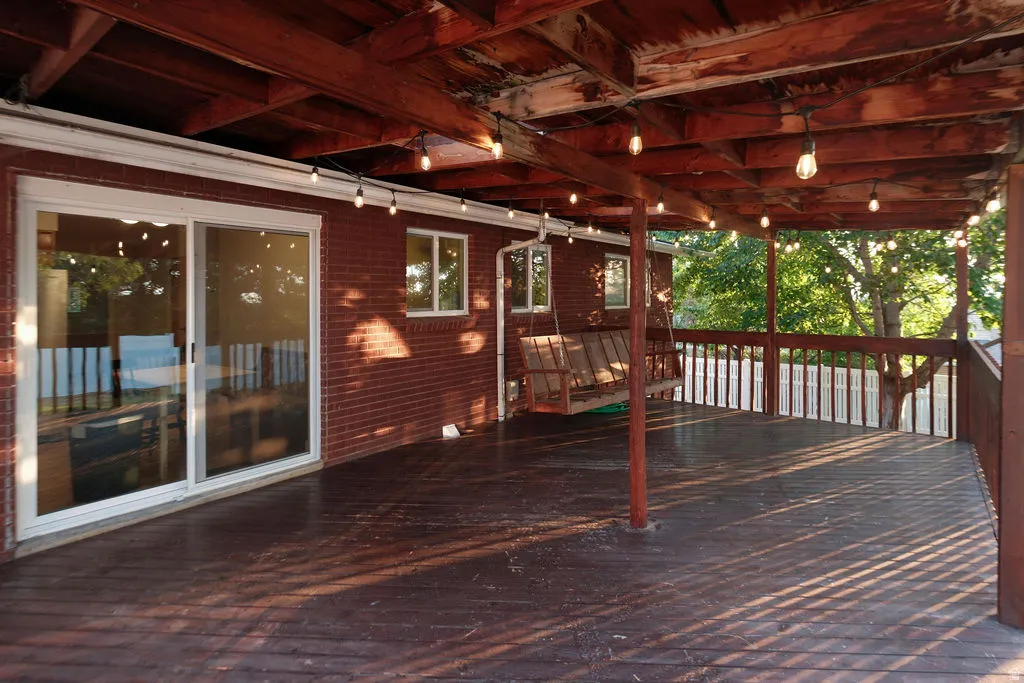 Expansive covered wood deck featuring string lighting and a wood railing