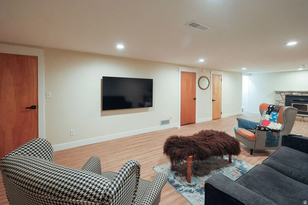Spacious living area featuring wood-finish flooring, recessed lighting, and a stone fireplace
