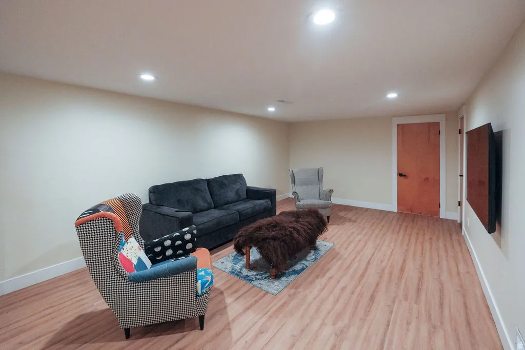 Spacious room featuring wood-finish flooring, recessed lighting, light-toned walls, and white baseboards