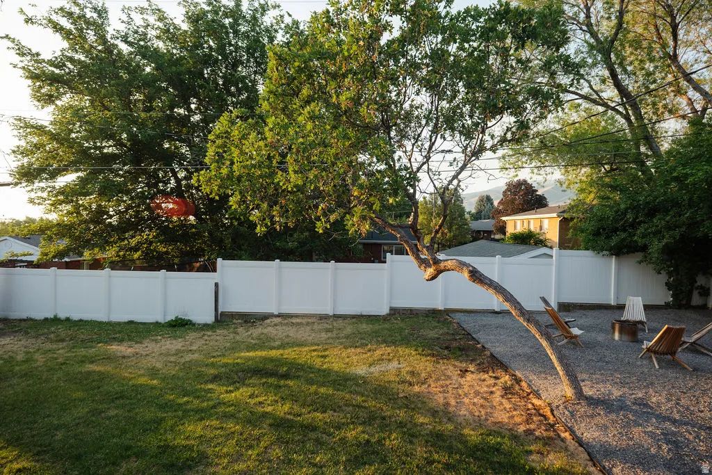 Expansive backyard featuring a gravel patio, fire pit, and white privacy fencing