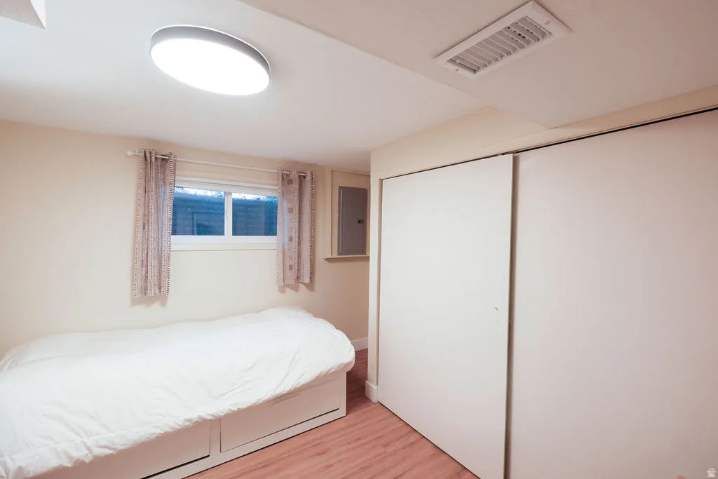 Bedroom featuring wood-finish flooring, a contemporary flush-mount ceiling light, and a window with a sill