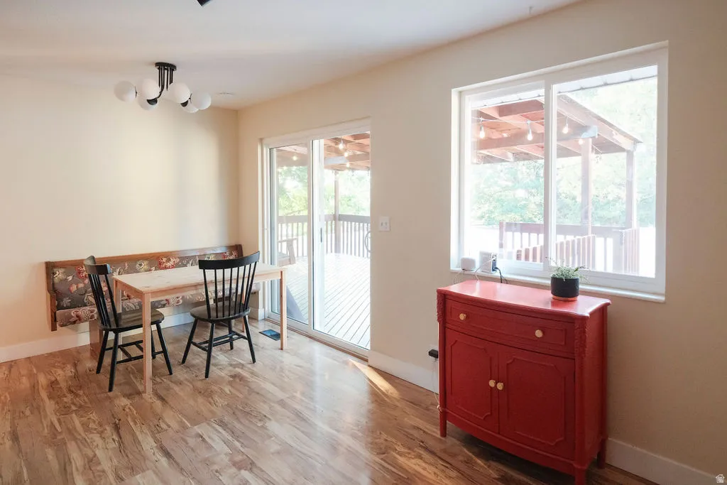 Spacious room featuring wood-finish flooring, a contemporary ceiling light fixture, and a built-in upholstered bench