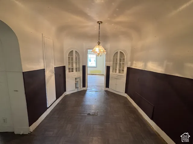 Arch-top built-in display cabinets flank a central passageway with a classic chandelier