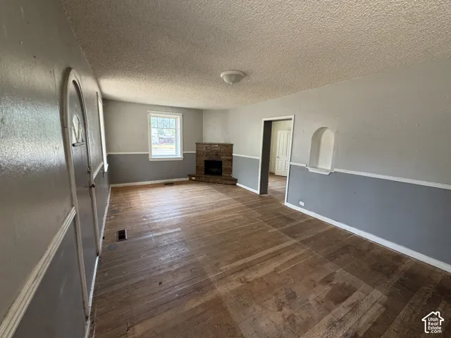 Living area featuring wood-finish flooring, a stone-clad corner fireplace, a window with exterior views, and a wall niche