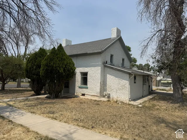 Stucco exterior featuring dual chimneys and a gabled roofline