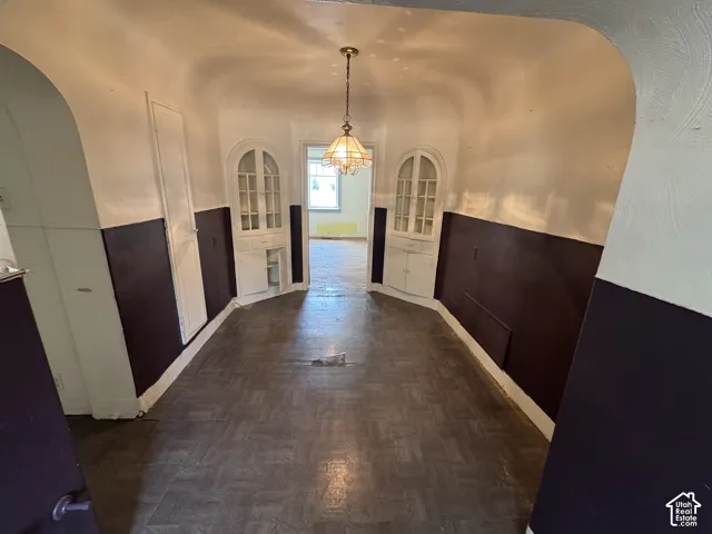 Hallway featuring parquet flooring and a central chandelier