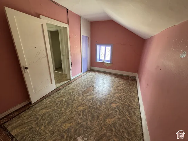 Room featuring a sloped ceiling, patterned flooring, and a single window