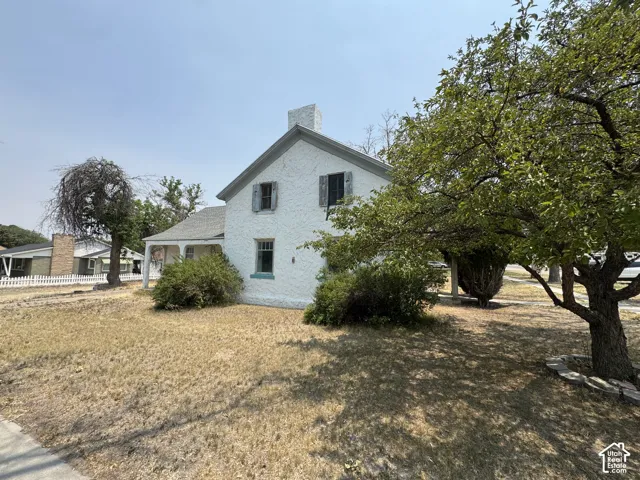 Two-story white stucco exterior featuring a prominent chimney and a covered front porch