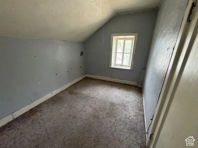 Room featuring a window with natural light, sloped ceiling, and existing carpet flooring