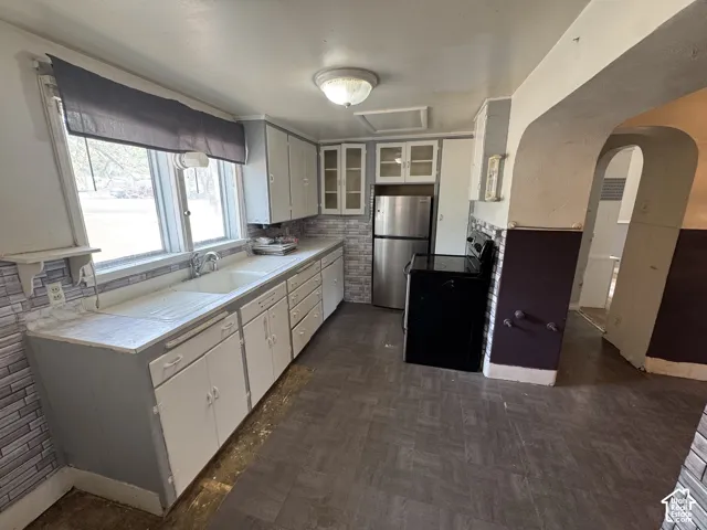 Kitchen featuring a dual basin sink, white cabinetry, a built-in range, and a stainless steel refrigerator