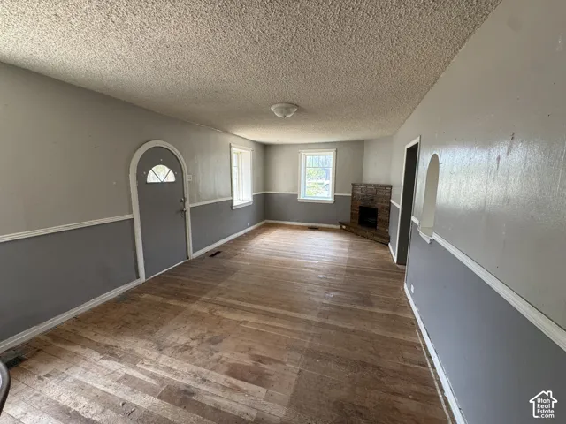 Spacious room featuring wood-finish flooring, a stone-clad fireplace, and two-tone wall paneling