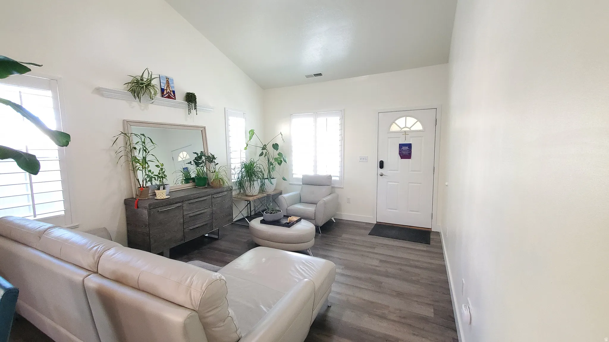 Living area featuring vaulted ceilings, light-hued walls, and wood-finish flooring